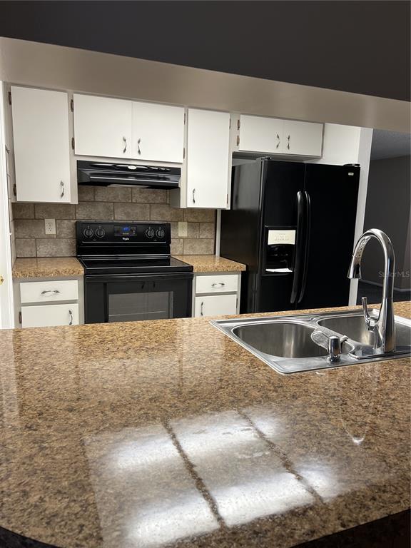 A kitchen features white cabinets, black appliances, and a brown speckled countertop with a sink — 4813 DOGWOOD STREET, NEW PORT RICHEY, FL