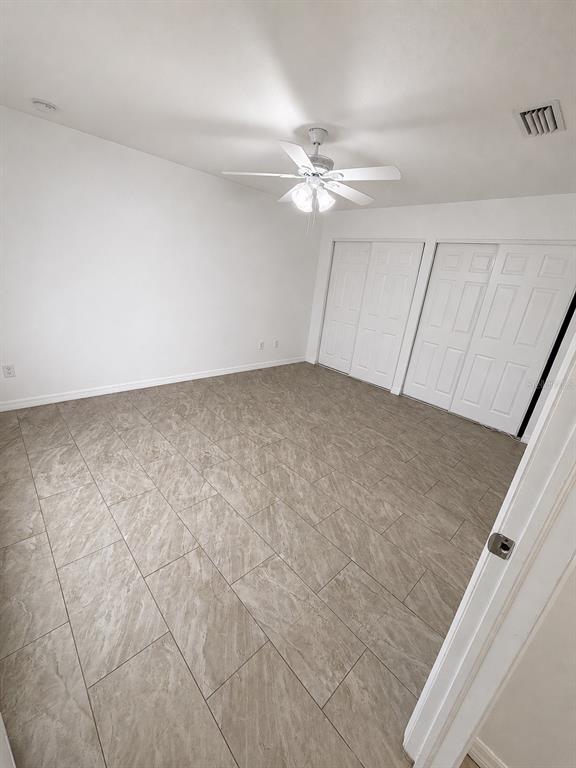 An empty bedroom features white walls, a ceiling fan, and light-colored tile flooring — 3019-3019 WALNUT COURT, LEESBURG, FL