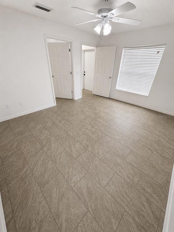 A bedroom with white walls, tile flooring, a ceiling fan, and two interior doors — 3019-3019 WALNUT COURT, LEESBURG, FL