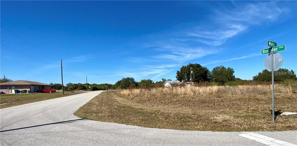 A street corner with a road, a vacant grassy lot, and a street sign — 165 WALDO STREET, PORT CHARLOTTE, FL
