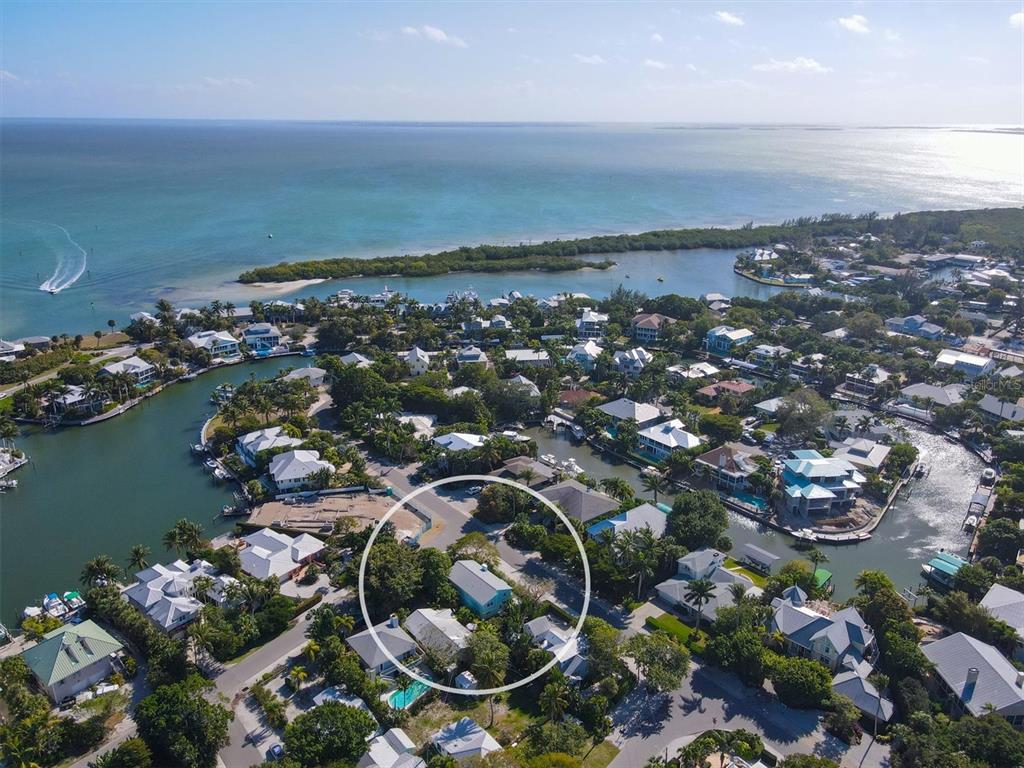 An aerial view shows a light blue house circled within a coastal residential neighborhood — 261 LEE AVENUE, BOCA GRANDE, FL