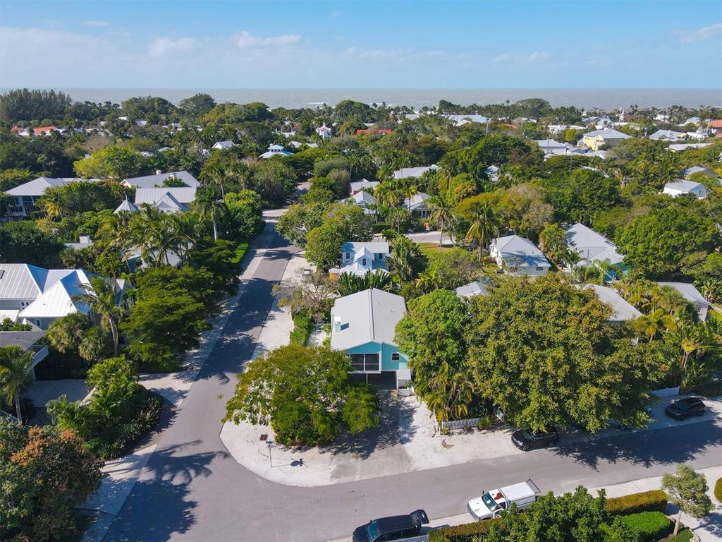An aerial view shows a light blue house nestled among lush trees near the coast — 261 LEE AVENUE, BOCA GRANDE, FL