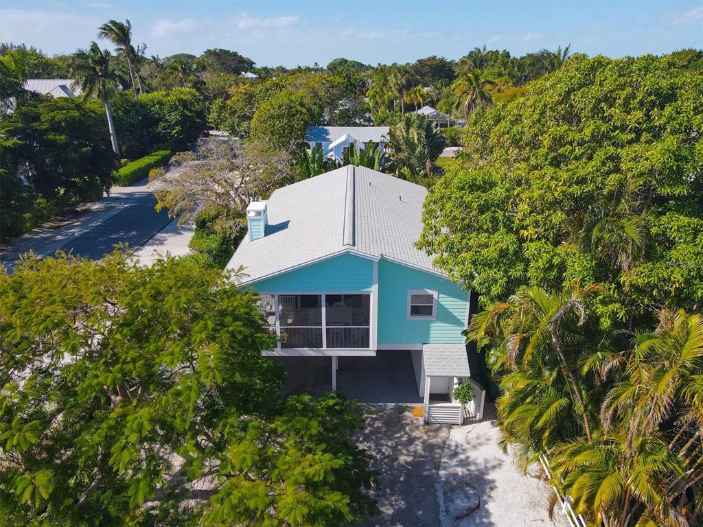 An elevated, light blue house with a metal roof surrounded by lush tropical trees — 261 LEE AVENUE, BOCA GRANDE, FL