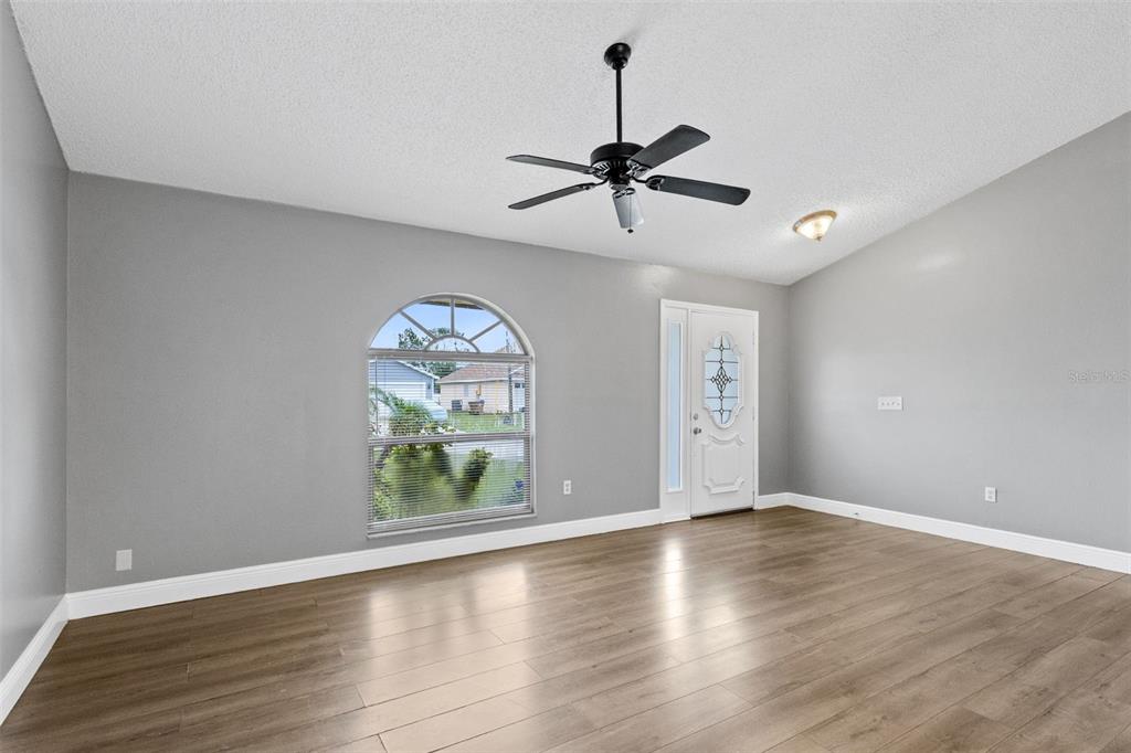 An empty room with gray walls, wood-look flooring, a ceiling fan, and an arched window — 1025 DERBYSHIRE DRIVE, KISSIMMEE, FL