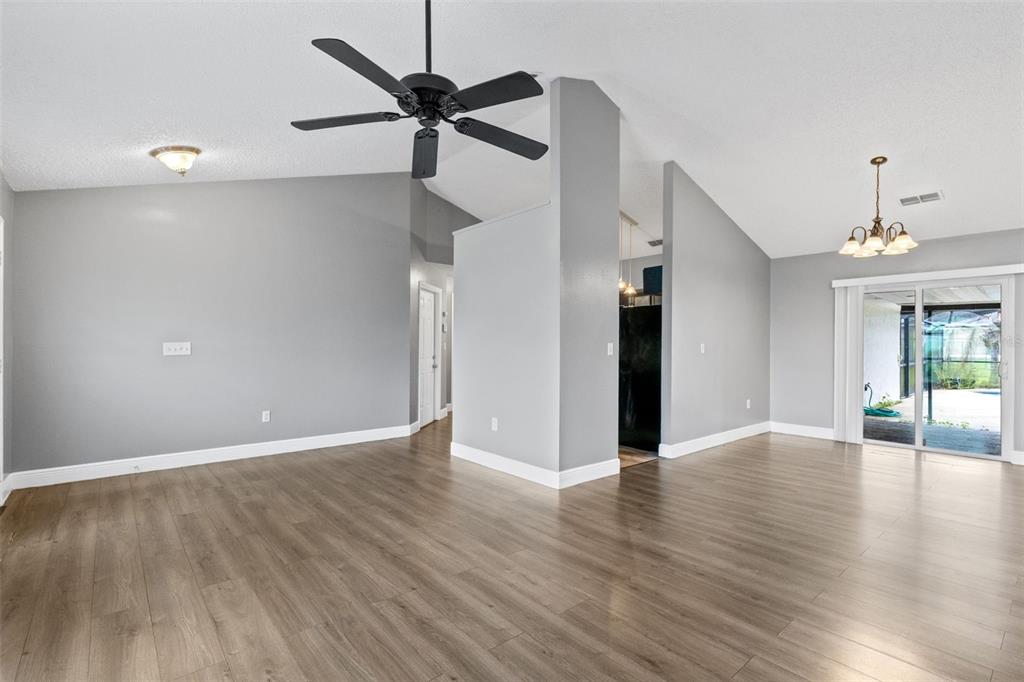 A living room with vaulted ceilings, gray walls, wood-look flooring, and a black ceiling fan — 1025 DERBYSHIRE DRIVE, KISSIMMEE, FL