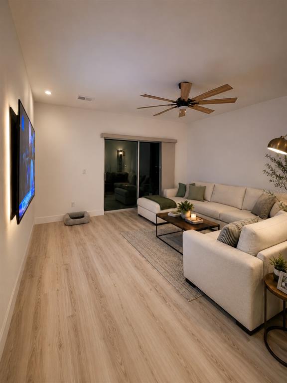 A living room features light wood flooring, a sectional sofa, and a wall-mounted television — 443 IRONSIDE TRAIL DRIVE, GROVELAND, FL
