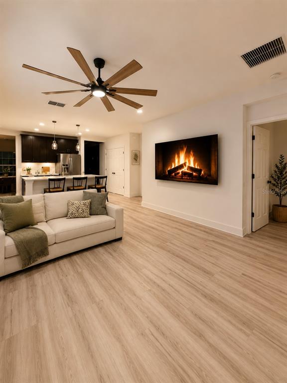A living room features light wood flooring, a white sofa, a ceiling fan, and a fireplace — 443 IRONSIDE TRAIL DRIVE, GROVELAND, FL