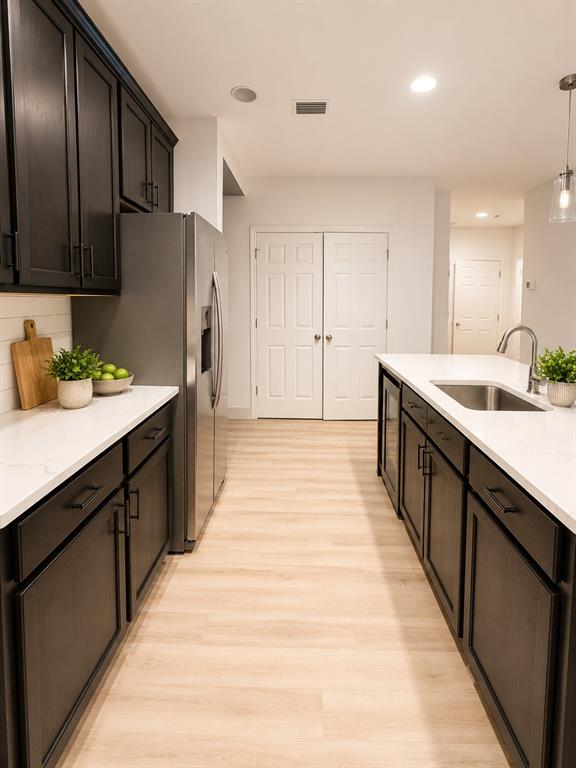 A kitchen features dark cabinets, white countertops, stainless steel appliances, and light wood-look flooring — 443 IRONSIDE TRAIL DRIVE, GROVELAND, FL