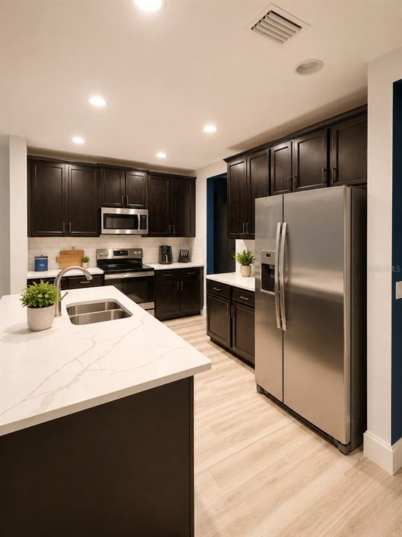 A kitchen features dark wood cabinets, stainless steel appliances, and a white quartz island countertop — 443 IRONSIDE TRAIL DRIVE, GROVELAND, FL