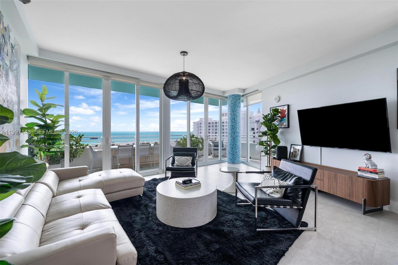 A modern living room features a white sectional, black chairs, and floor-to-ceiling windows overlooking the ocean — 226 Ocean Dr # 8F, Miami Beach FL 33139, MIAMI BEACH, FL