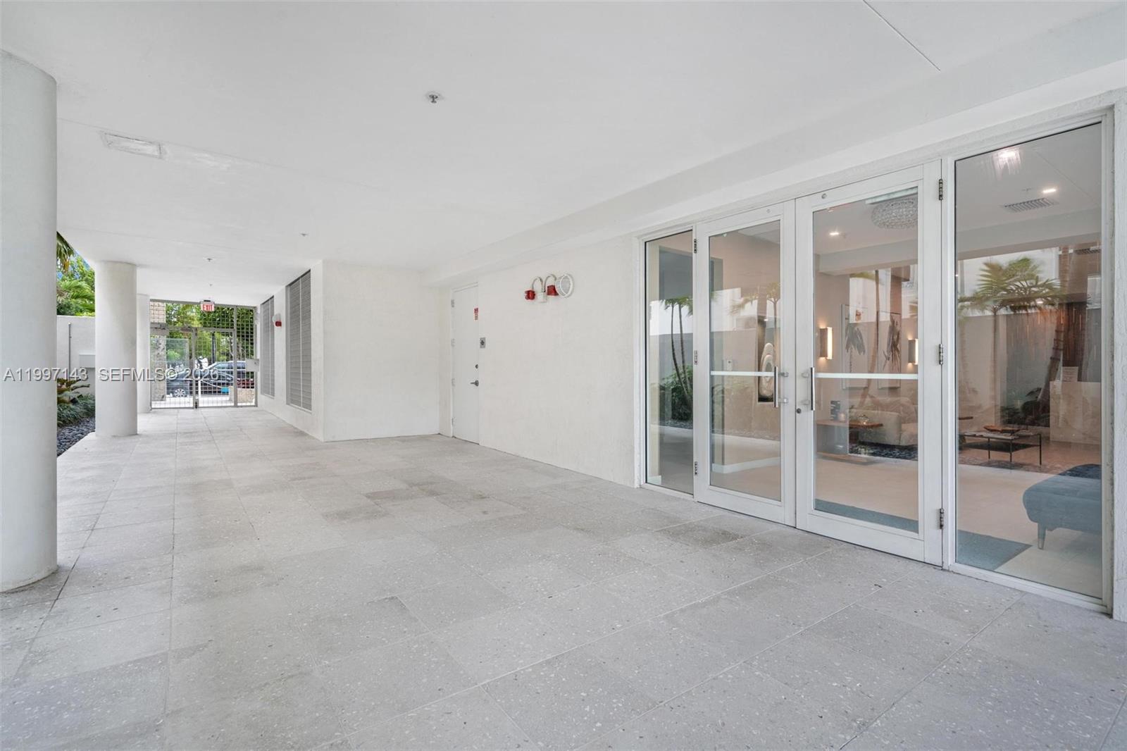 A covered outdoor patio features light-colored tile flooring and glass doors leading into a building — 226 Ocean Dr # 8F, Miami Beach FL 33139, MIAMI BEACH, FL