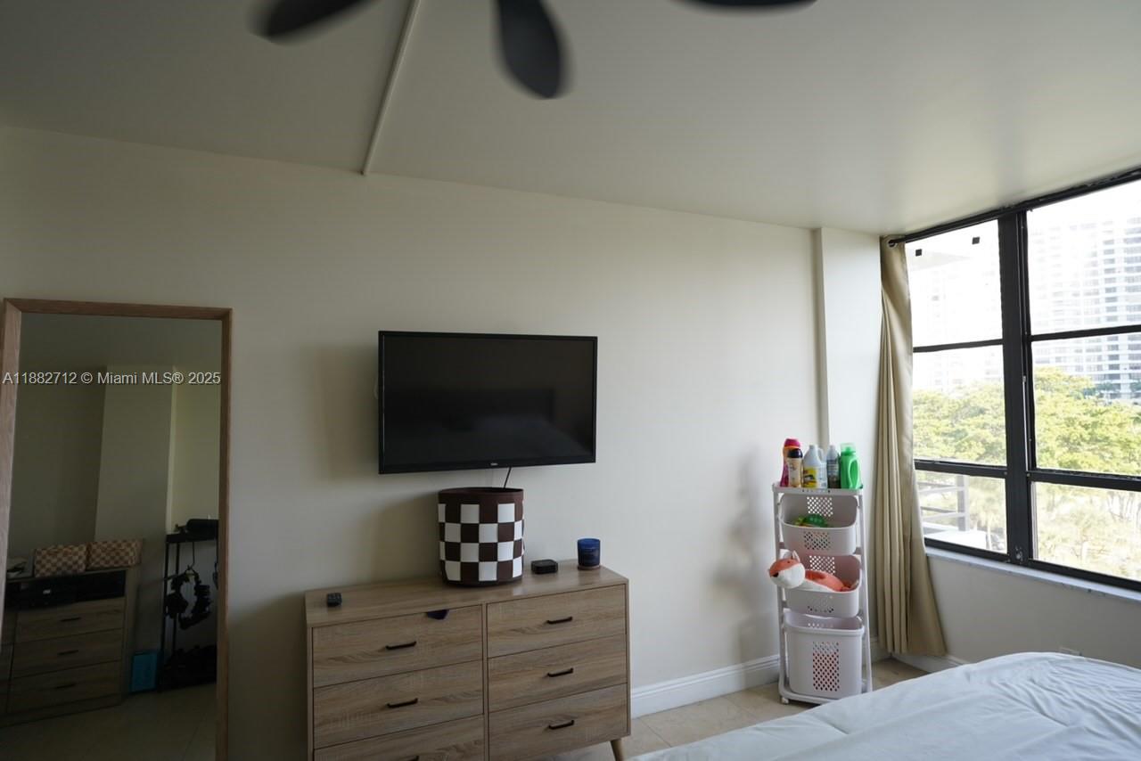 A bedroom features a dresser with a wall-mounted television, a mirror, and a storage cart — 500 Three Islands Blvd # 226, Hallandale Beach FL 33009, HALLANDALE BEACH, FL