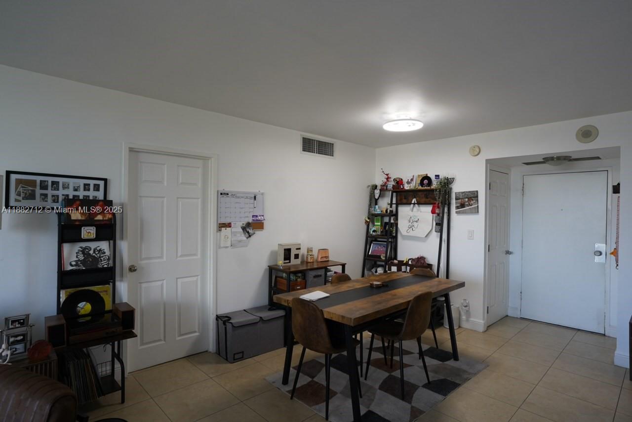 A dining area features a wooden table, chairs, and shelving against a white wall — 500 Three Islands Blvd # 226, Hallandale Beach FL 33009, HALLANDALE BEACH, FL