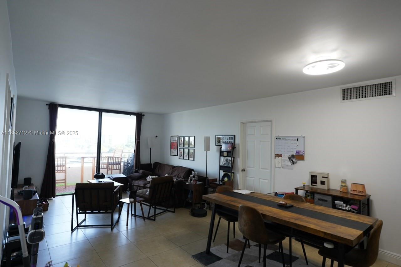 A living and dining area features tile floors, a wooden table, and a balcony view — 500 Three Islands Blvd # 226, Hallandale Beach FL 33009, HALLANDALE BEACH, FL