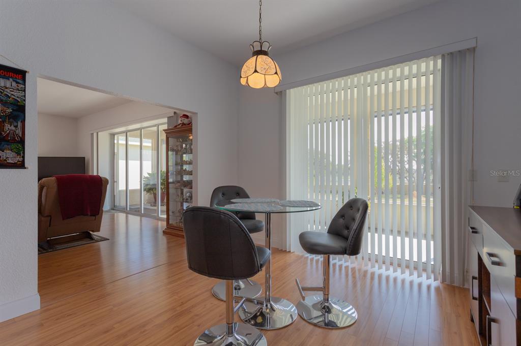 A dining area features a glass table, three gray stools, and vertical blinds — 11395 SE 108TH TERRACE ROAD, BELLEVIEW, FL