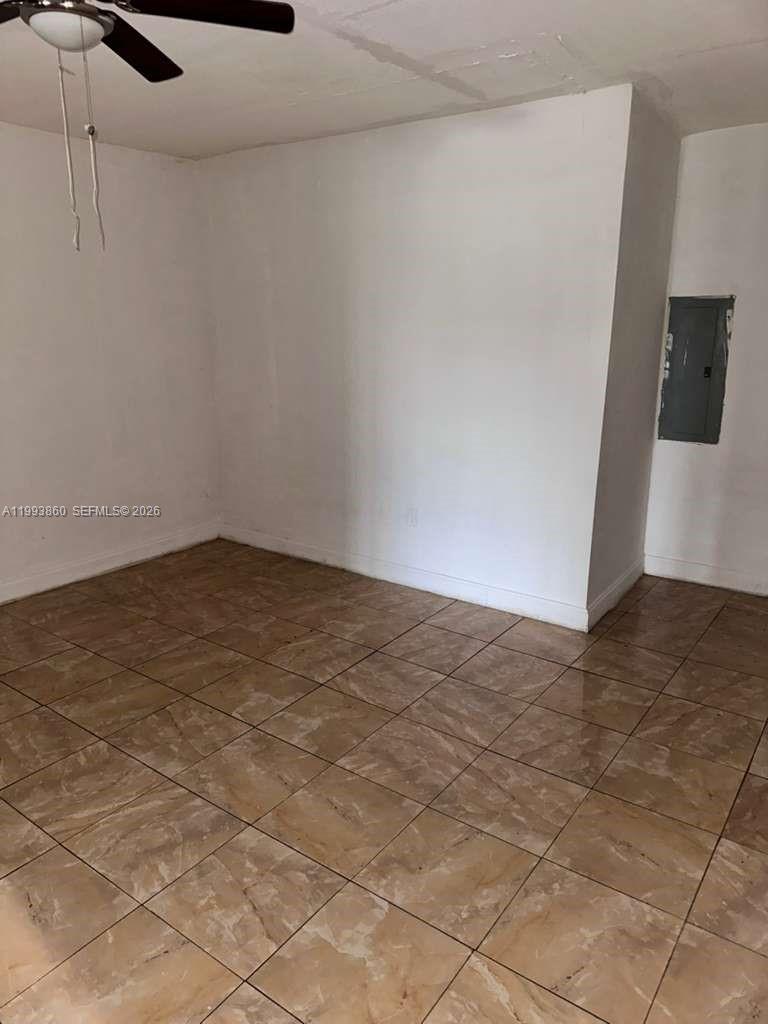 An empty room features tan tiled flooring, white walls, and a ceiling fan — 576 NW 147th St # 576, Miami FL 33168, MIAMI, FL