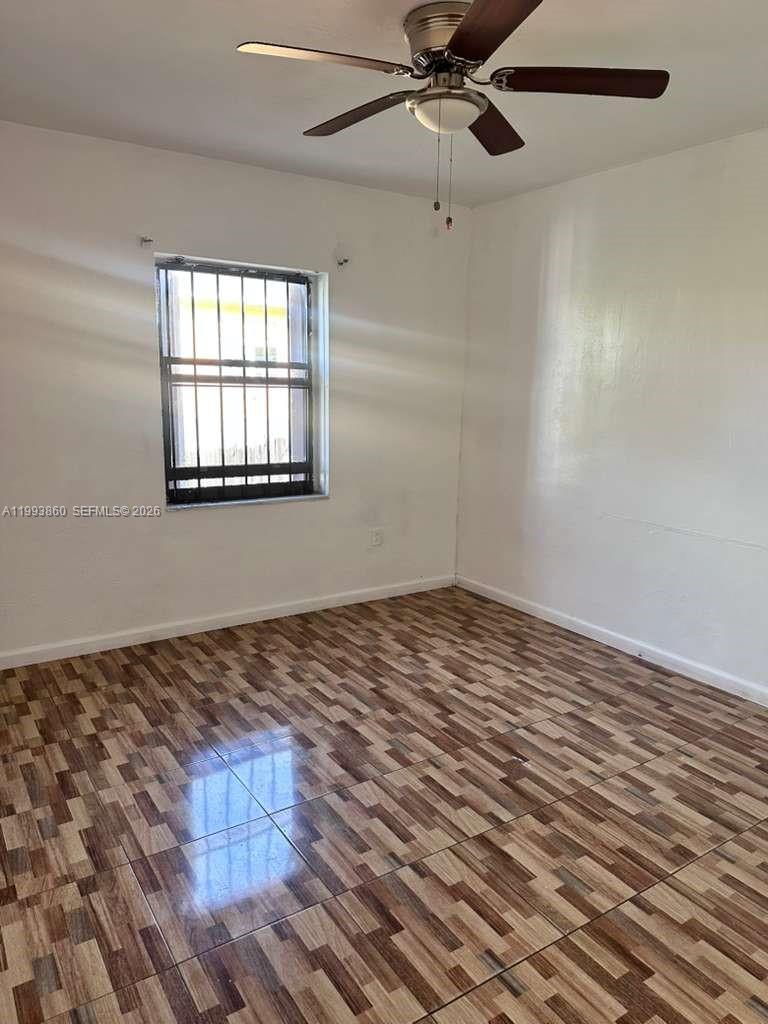 An empty room features white walls, a ceiling fan, and brown patterned tile flooring — 576 NW 147th St # 576, Miami FL 33168, MIAMI, FL