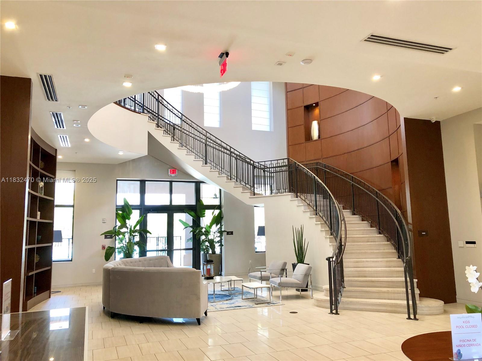A spacious lobby features a curved staircase, light tile flooring, and a seating area — 8031 NW 104th Ave # 21, Doral FL 33178, DORAL, FL