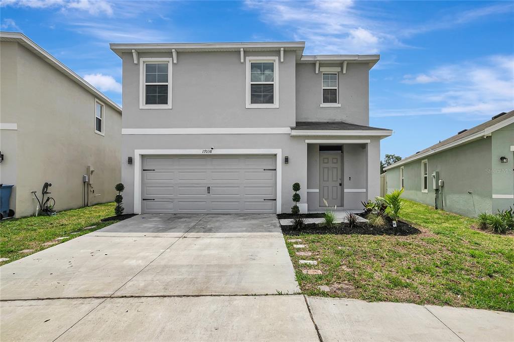 A two-story gray house with a two-car garage and a front entrance under a porch — 17038 WAVE TRESSLE PLACE, WIMAUMA, FL