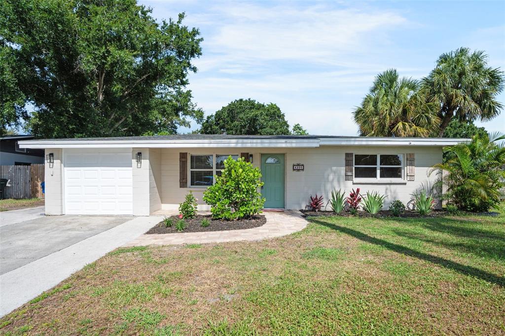 A single-story house with a white garage, light siding, and a green front door — 4200 DES PLAINES DRIVE, SARASOTA, FL