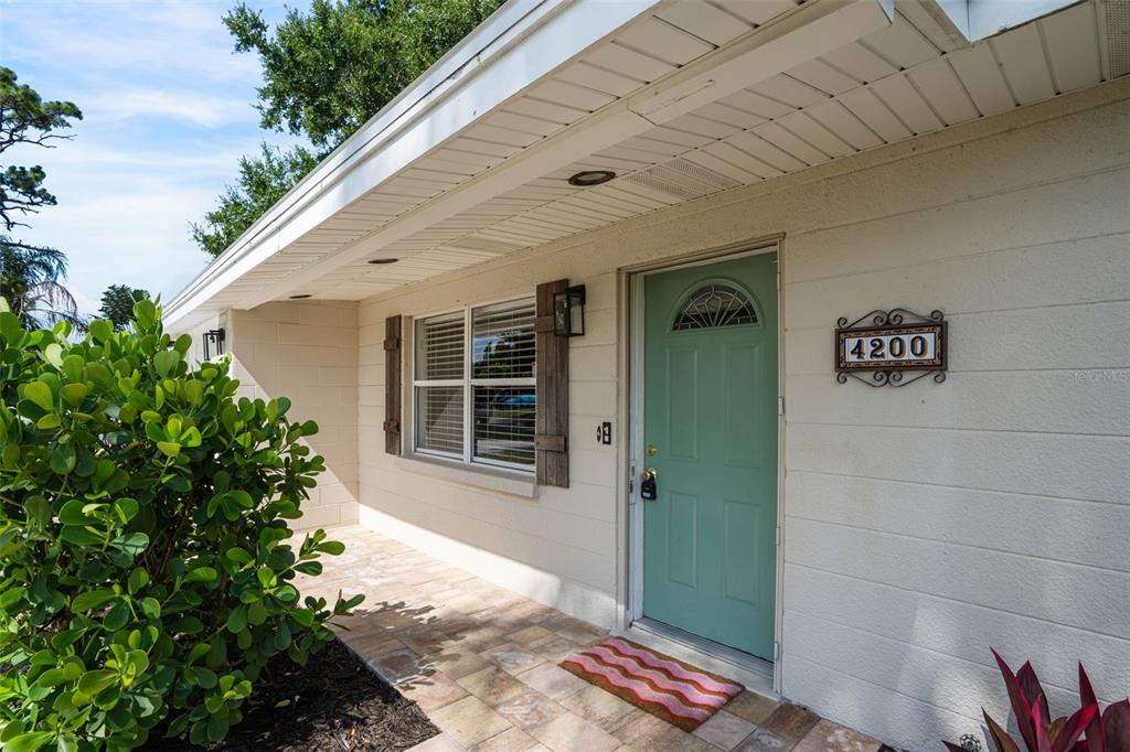 A light green front door with a house number plaque sits on a tiled porch — 4200 DES PLAINES DRIVE, SARASOTA, FL