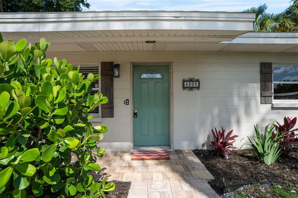 The exterior of a house features a light green front door and a stone walkway — 4200 DES PLAINES DRIVE, SARASOTA, FL