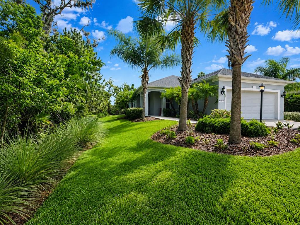 A single-story house with a two-car garage, palm trees, and a manicured lawn — 10806 PINE BLUFF GLEN, PARRISH, FL
