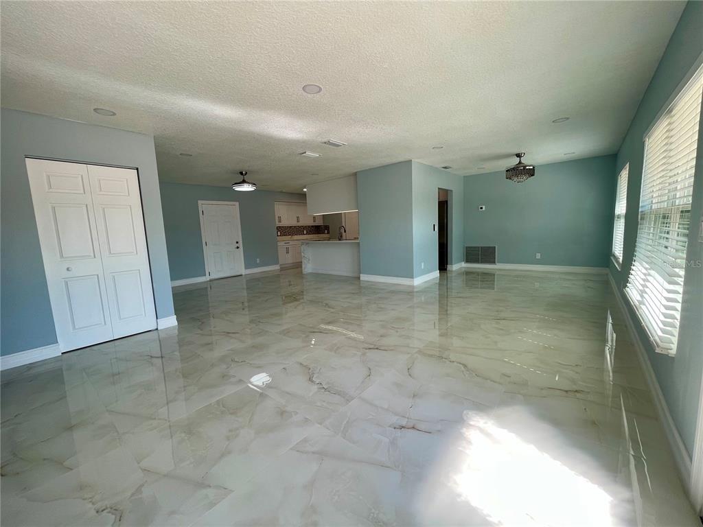 An open-concept living area features glossy marble-look tile flooring and light blue walls — 8503 WOODWICK COURT, TAMPA, FL