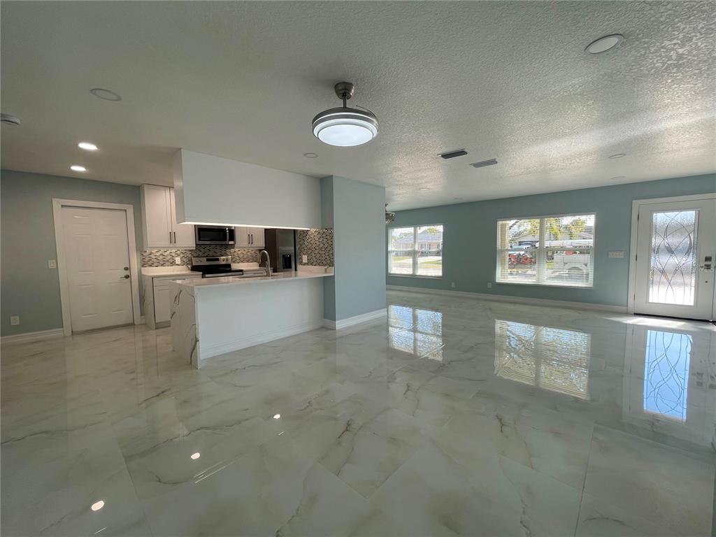 An open-concept living area features light blue walls, white cabinetry, and polished marble-look tile flooring — 8503 WOODWICK COURT, TAMPA, FL