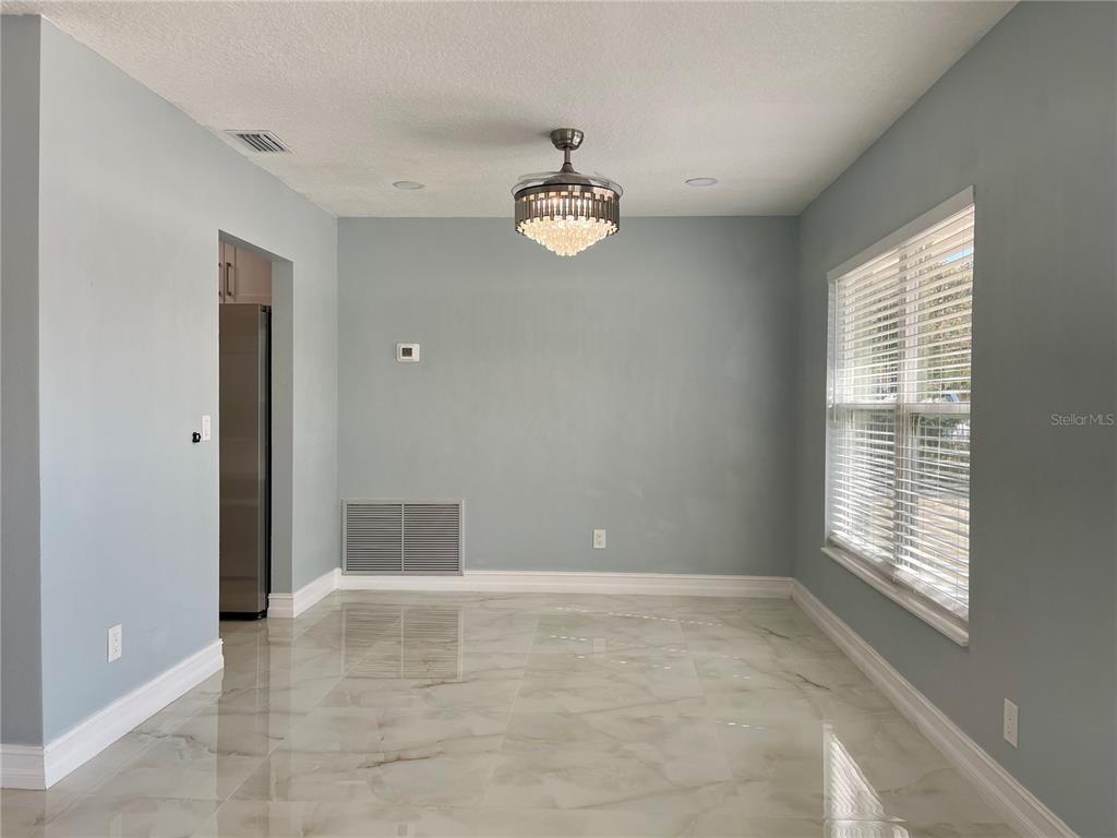 A dining room features light blue walls, white trim, tile flooring, and a crystal ceiling fan — 8503 WOODWICK COURT, TAMPA, FL