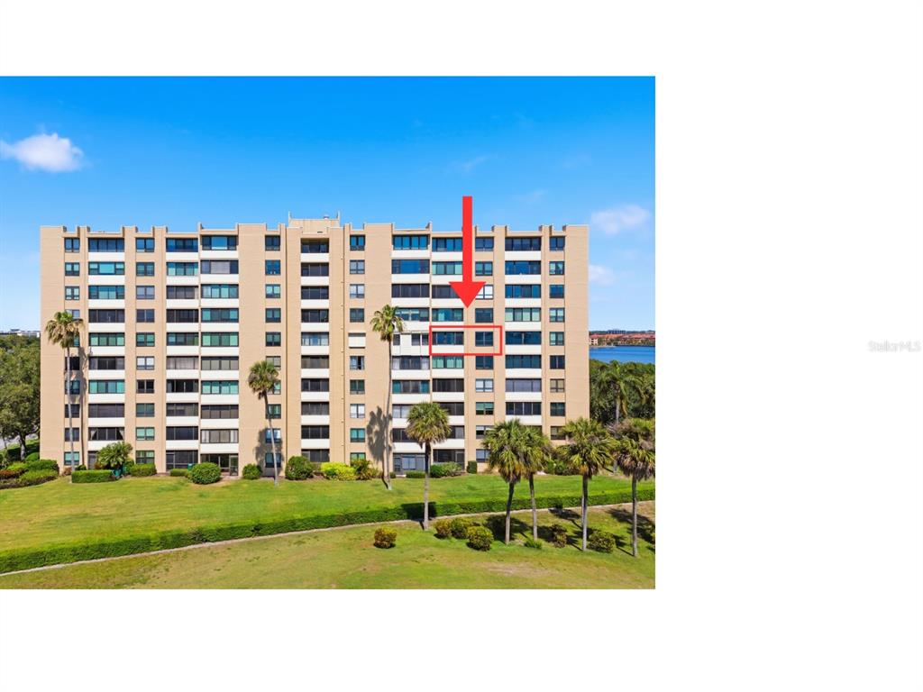 An exterior view of a multi-story apartment building with a red arrow pointing to a unit — 2616 COVE CAY DRIVE UNIT 602, CLEARWATER, FL
