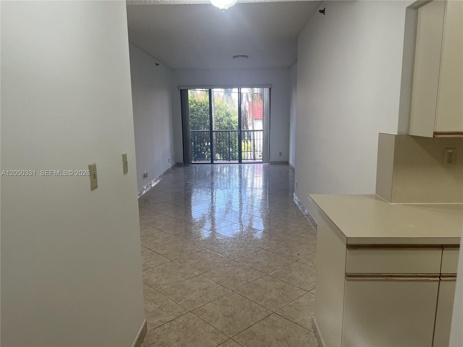 A tiled living area leads to a balcony with a view of trees — 8816 Collins Ave # 105, Surfside FL 33154, SURFSIDE, FL