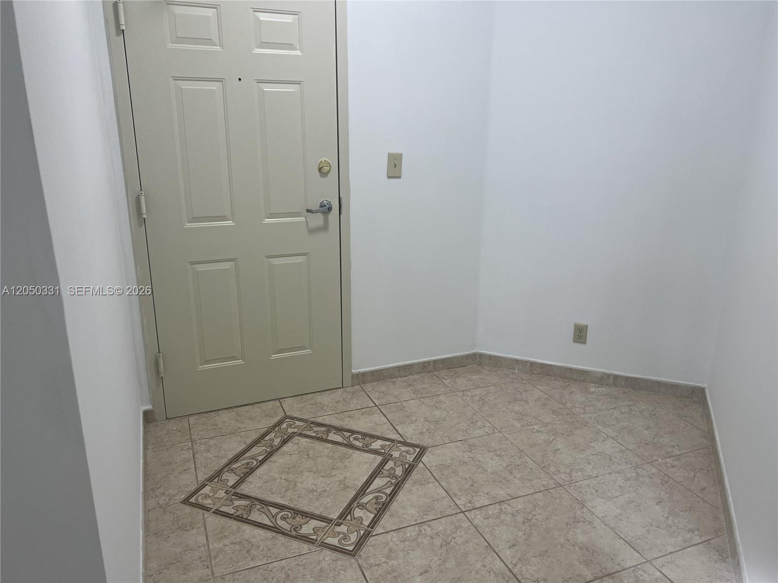 An entryway features a beige door, white walls, and light-colored tile flooring with decorative inlays — 8816 Collins Ave # 105, Surfside FL 33154, SURFSIDE, FL