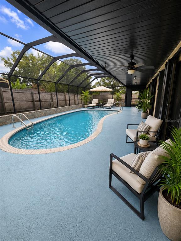 A screened-in patio features a kidney-shaped swimming pool, lounge chairs, and a ceiling fan — 7054 LEXINGTON CIRCLE, BROOKSVILLE, FL