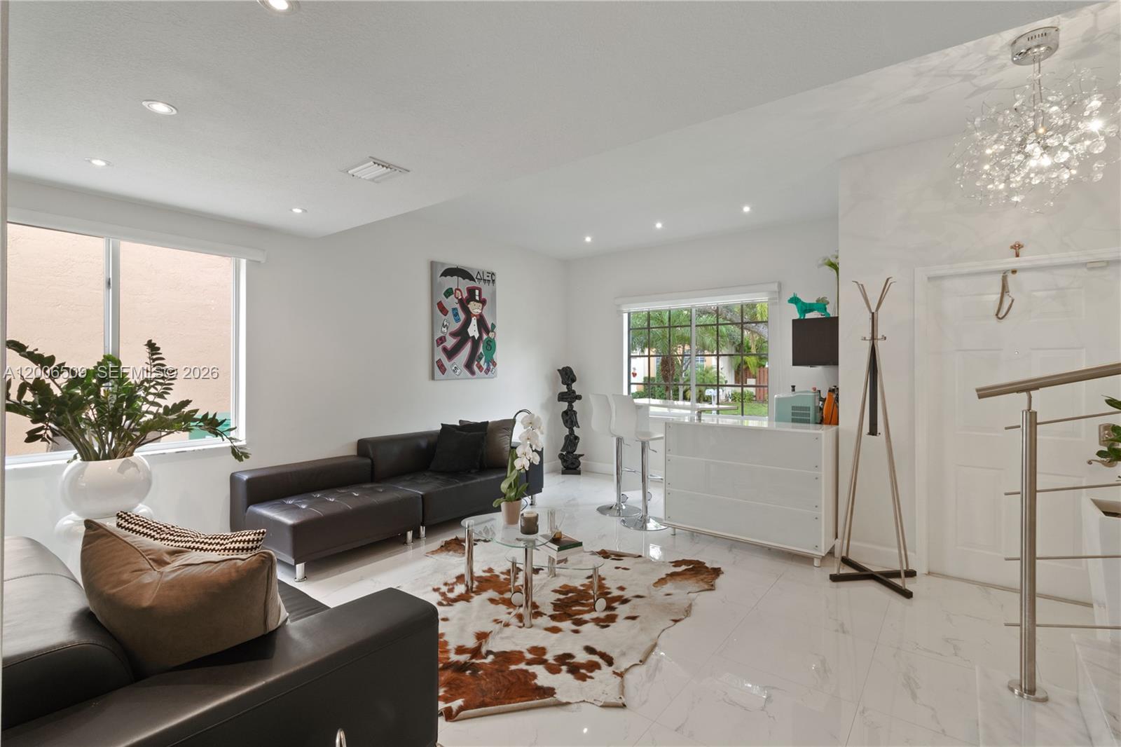 A modern living room features white tile floors, black leather sofas, and a cowhide rug — 10842 NW 53rd Ln, Doral FL 33178, DORAL, FL