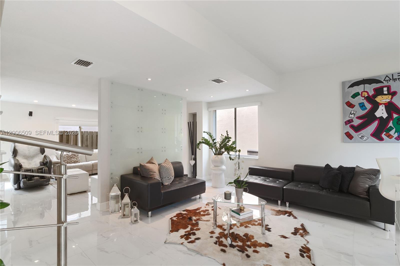 A modern living room features white marble floors, black leather sofas, and a cowhide rug — 10842 NW 53rd Ln, Doral FL 33178, DORAL, FL