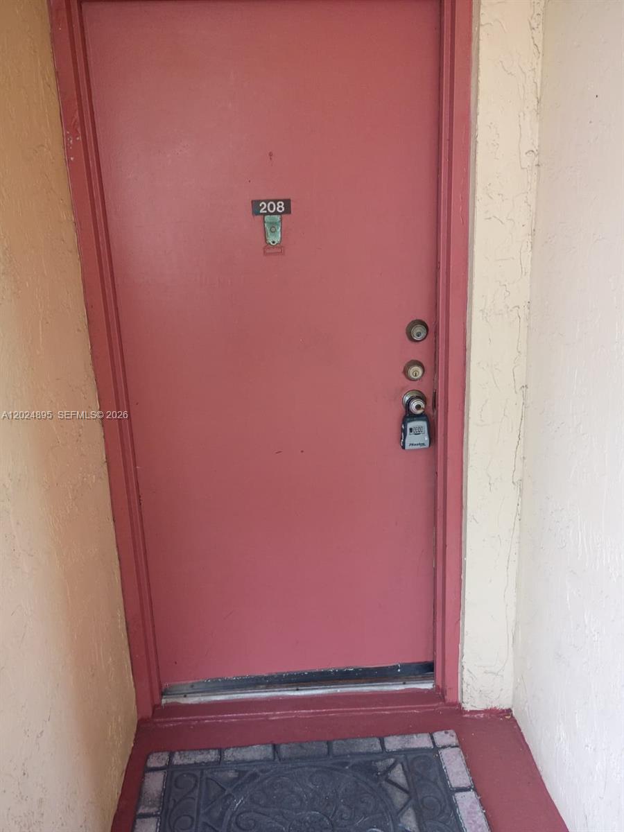 A pink door with a number 208 sign and a lockbox is shown — 3399 Foxcroft Rd # 208, Miramar FL 33025, MIRAMAR, FL