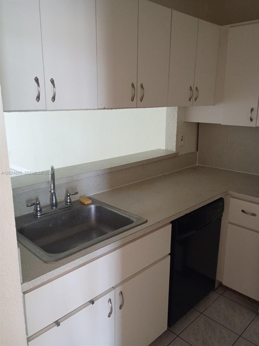 A kitchen features white cabinets, a stainless steel sink, and a black dishwasher — 3399 Foxcroft Rd # 208, Miramar FL 33025, MIRAMAR, FL