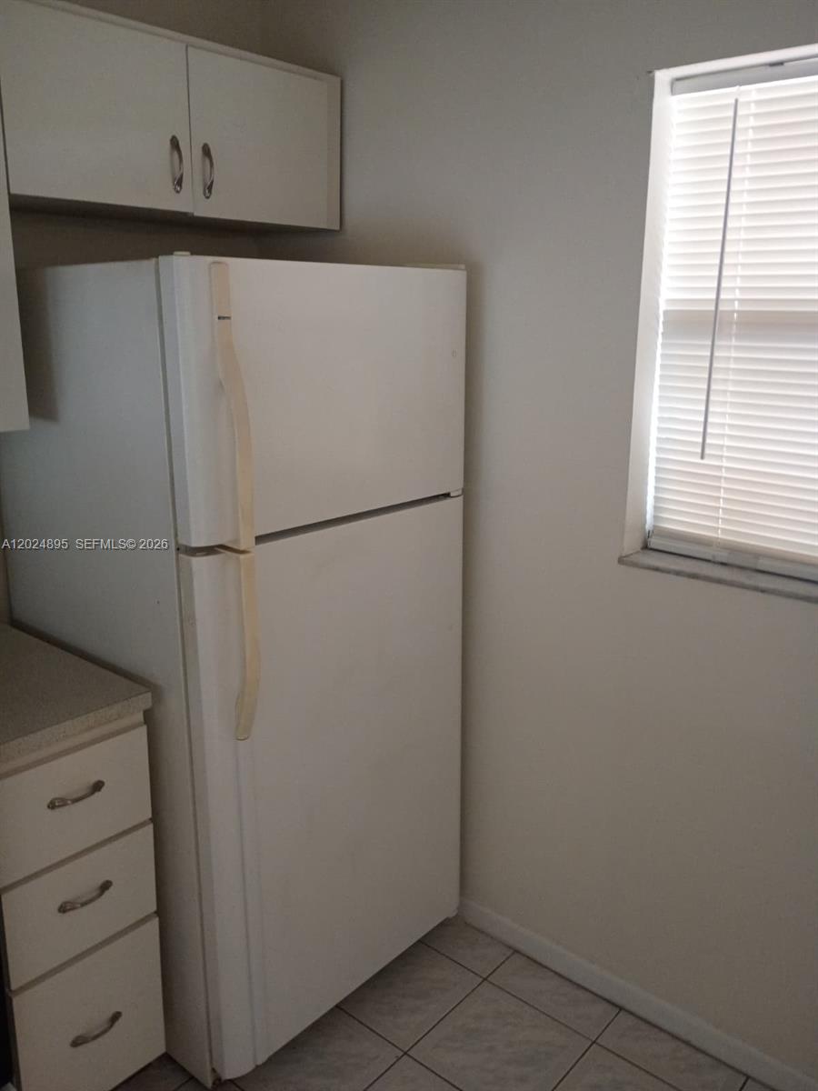 A white refrigerator stands next to a window and a set of kitchen cabinets — 3399 Foxcroft Rd # 208, Miramar FL 33025, MIRAMAR, FL