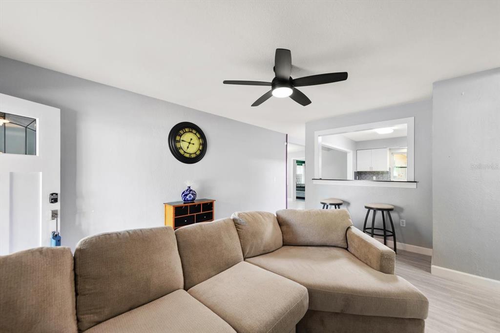 A living room features a beige sectional sofa, a ceiling fan, and a wall clock — 611 11TH STREET NW, LARGO, FL