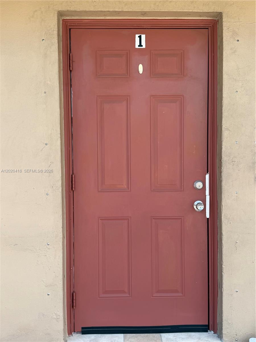 A red, six-panel exterior door labeled with the number one is set in a wall — 2924 NW 132nd Ter # 1, Opa-Locka FL 33054, OPA-LOCKA, FL
