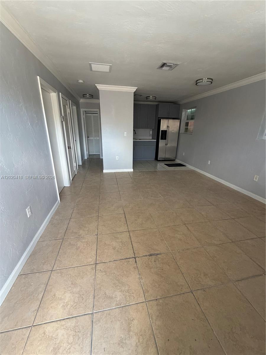 An open-concept living area features light-colored tile flooring, gray walls, and a kitchen with stainless steel appliances — 2924 NW 132nd Ter # 1, Opa-Locka FL 33054, OPA-LOCKA, FL
