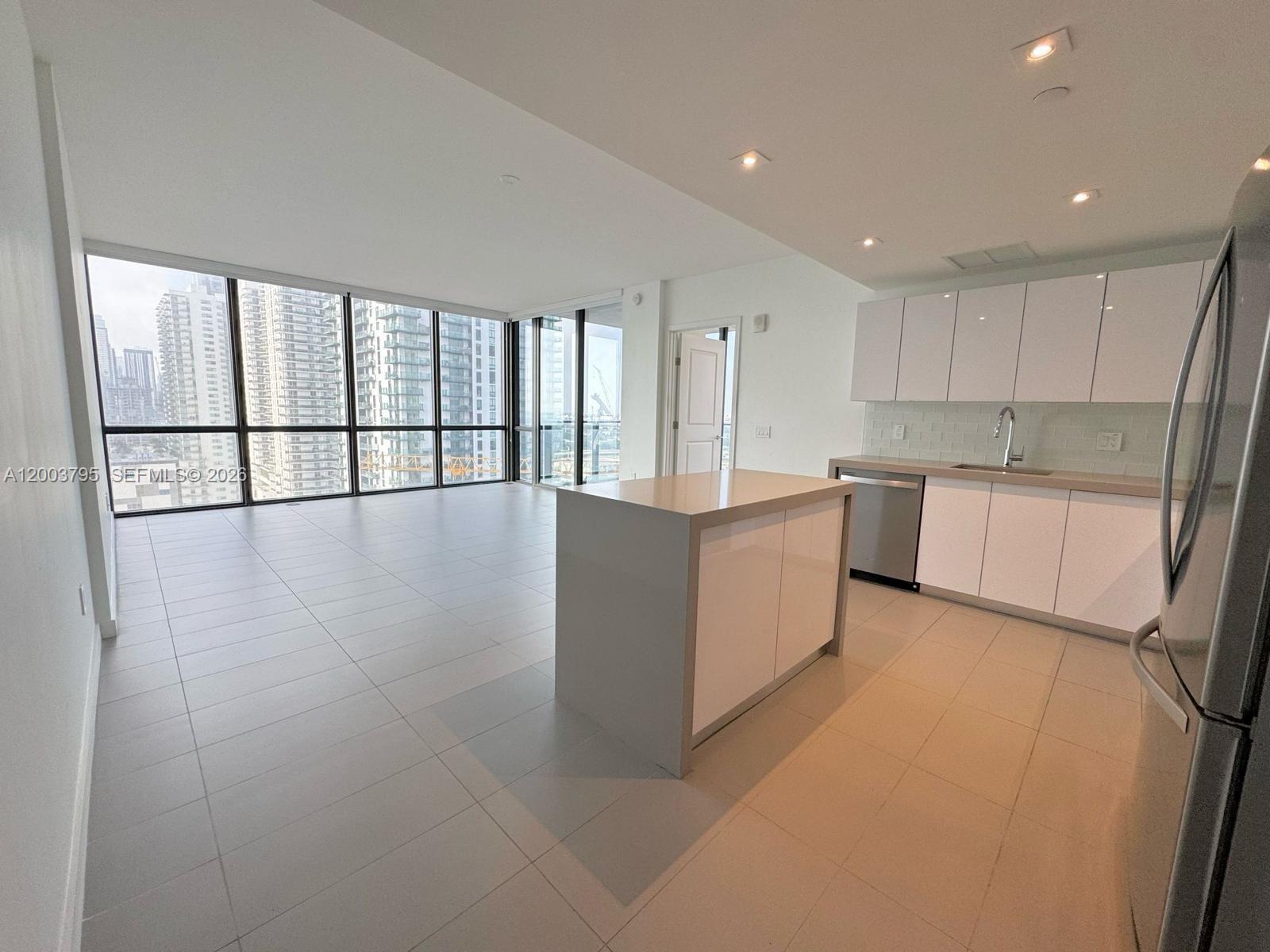 A modern kitchen and living area features white cabinetry, a central island, and floor-to-ceiling windows — 1600 NE 1st Ave # 1110, Miami FL 33132, MIAMI, FL