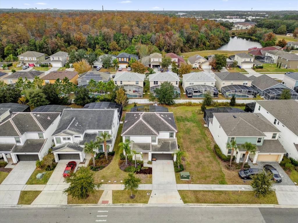 An aerial view shows suburban houses with driveways, screened-in pools, and a nearby pond — 4501 MONADO DRIVE, KISSIMMEE, FL