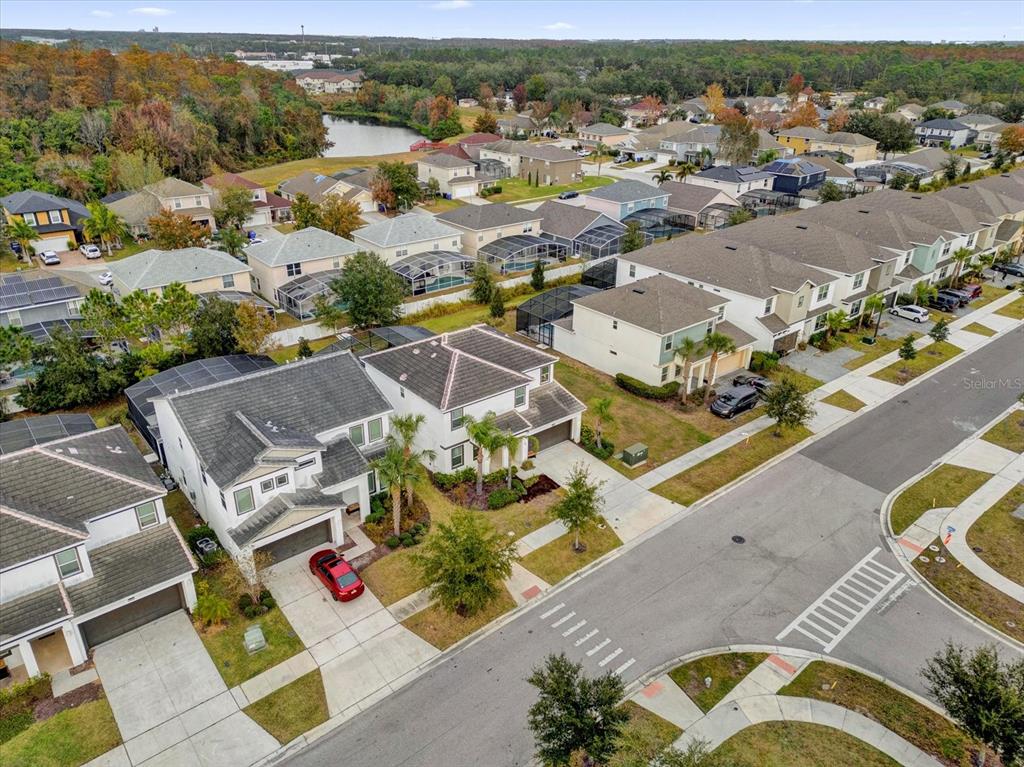 An aerial view shows a suburban neighborhood with houses, driveways, and a nearby pond — 4501 MONADO DRIVE, KISSIMMEE, FL