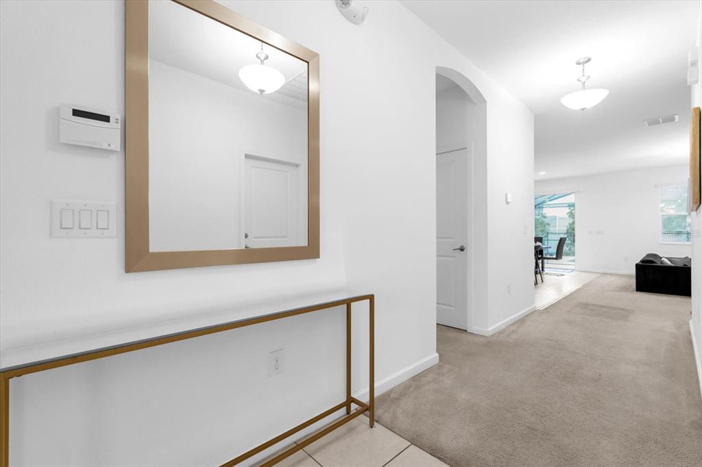 A hallway features a gold-framed mirror, a console table, and carpeted flooring leading to living areas — 4501 MONADO DRIVE, KISSIMMEE, FL