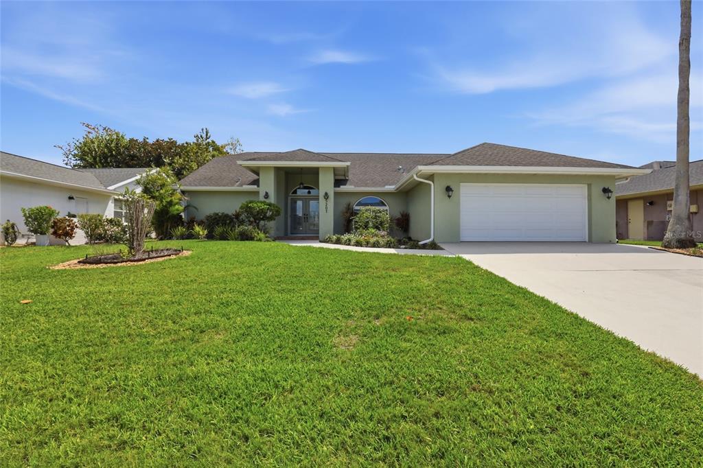 A single-story house with a green exterior, a two-car garage, and a front lawn — 5207 86TH STREET COURT W, BRADENTON, FL