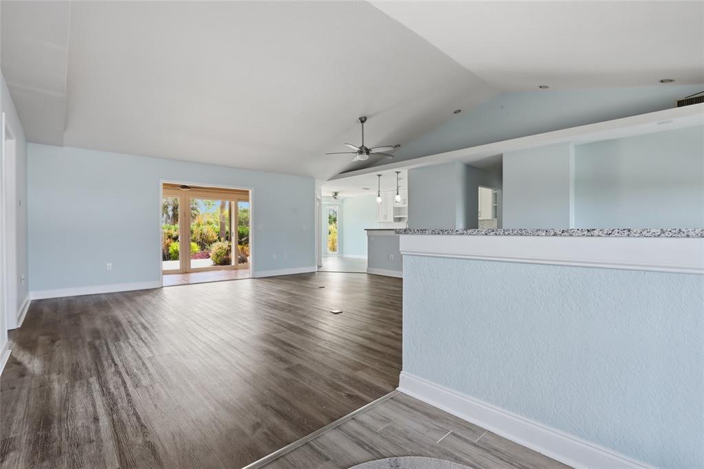 A spacious living area with light blue walls, wood-look flooring, and a sliding glass door — 5207 86TH STREET COURT W, BRADENTON, FL