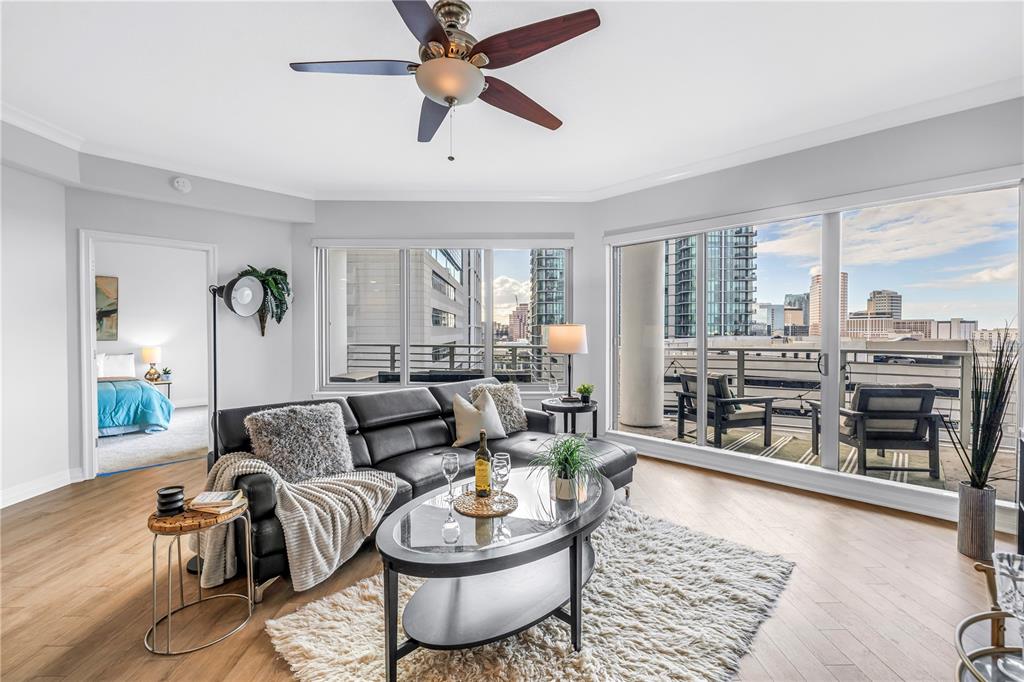 A living room with a black leather sectional, glass coffee table, and balcony with city views — 449 S 12TH STREET UNIT 1205, TAMPA, FL