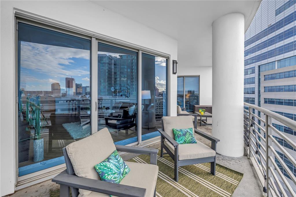 A balcony with two chairs, a striped rug, and sliding glass doors overlooking a city — 449 S 12TH STREET UNIT 1205, TAMPA, FL